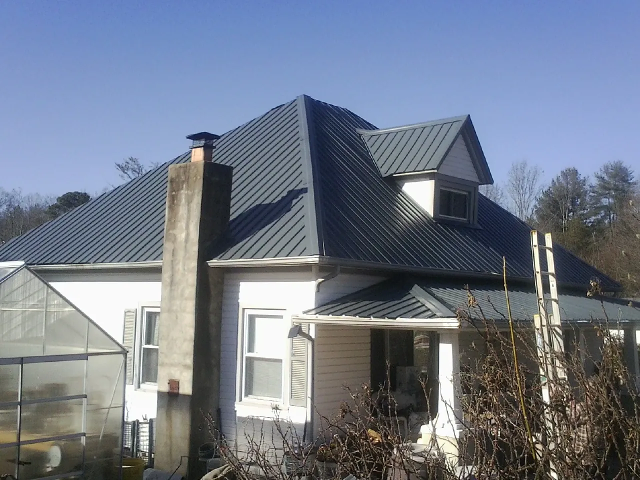 Dark blue standing seam metal roof on a white farmhouse with dormer — Slate & Tile Roof Repair by Roofing Brothers in West Suffield