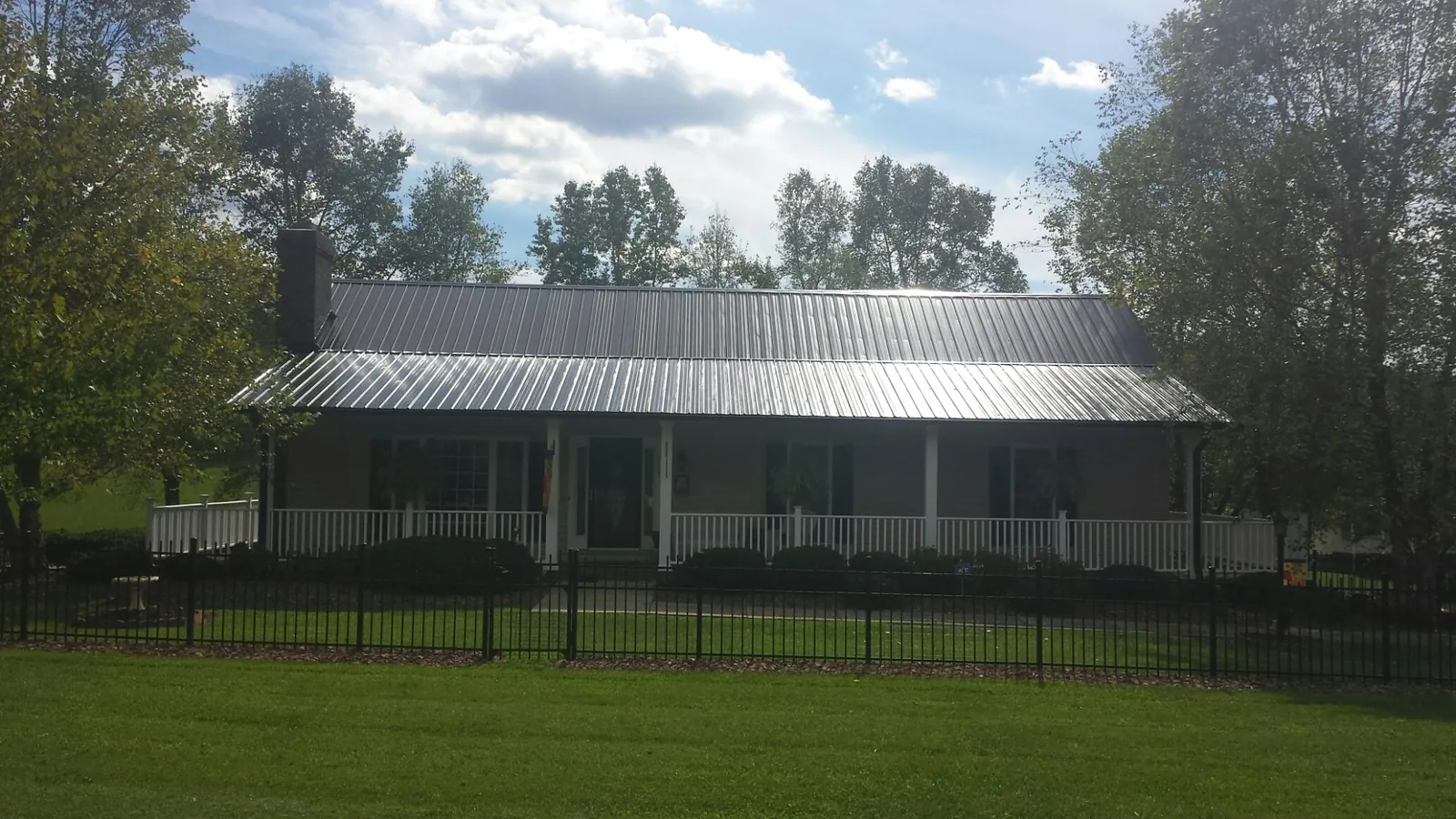 Gray metal roof on a brick ranch with a full width front porch — Gutter Guard Installation work by our crew in West Suffield