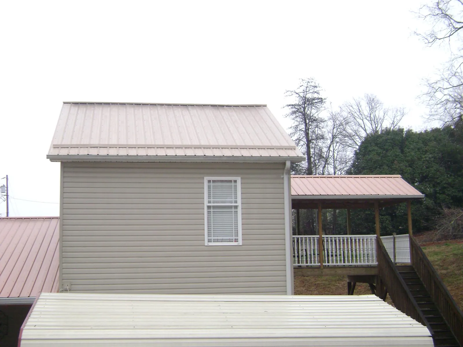 Tan metal roofs on a two story addition and attached porch, from a Roof Replacement job in West Suffield
